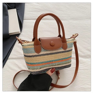 Detail of colorful striped straw woven bag with brown leather flap and golden hardware