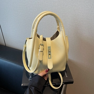 Sac seau en cuir jaune pâle avec motif litchi, détails dorés et bandoulière réglable