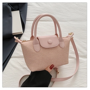 Detail of pink woven straw handbag featuring premium leather flap and detachable shoulder strap