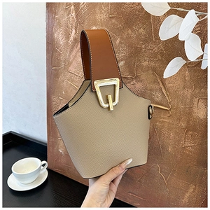 Detail of beige lychee textured bucket bag with brown handle and gold buckle