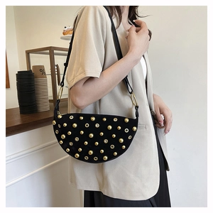 Detail of black crescent shoulder bag with gold rivets and metallic ring connector