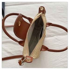Detail view of woven straw bag with PU leather trim, zipper closure, and inner lining