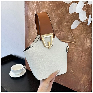Close-up of cream pebble leather bucket bag with brown handle and gold hardware detail