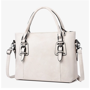 Détail du sac cabas blanc cassé montrant la texture cuir grainé et les boucles argentées