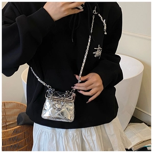 Detail shot of mini silver quilted chain bag with shiny metallic finish on female model