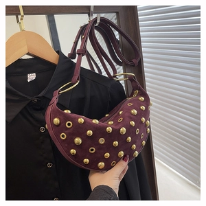 Detail of burgundy suede dumpling bag featuring vintage gold studs and eyelet rivets