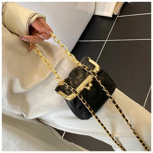 Detailed macro of black quilted mini bag with retro metal clasp and gold chain handle