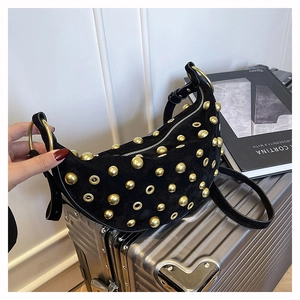 Detailed close-up of a black suede dumpling bag with golden metal studs and eyelets