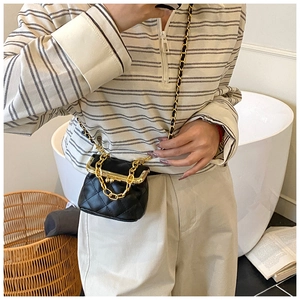 Close-up of mini black quilted crossbody bag with gold chain and vintage clasp closure
