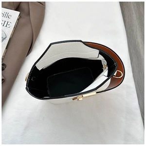 Detailed interior of a two-tone bucket bag showing a zipper pocket and golden hardware