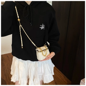 Mini white quilted crossbody bag with gold chain strap shown on a casual model outfit