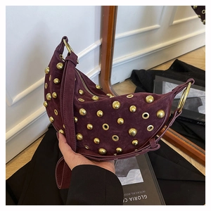 Macro detail of wine red suede crescent bag with gold rivets and metallic eyelets
