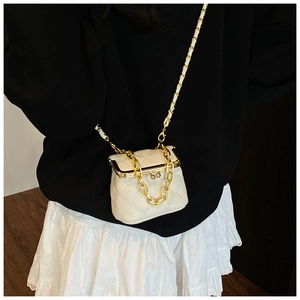 Detailed back view of a white quilted mini bag with gold chain strap on an outfit