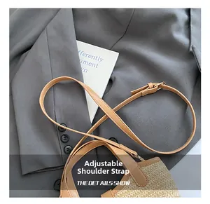 Close-up of woven bucket bag featuring adjustable brown leather strap with metal buckle