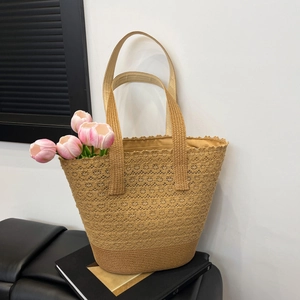 Large beige woven straw tote bag with cutout patterns and shoulder straps for beach