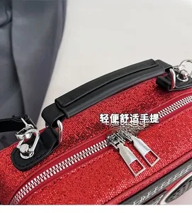 Detail of red sequin radio-shaped bag showing dual zippers and black handle texture
