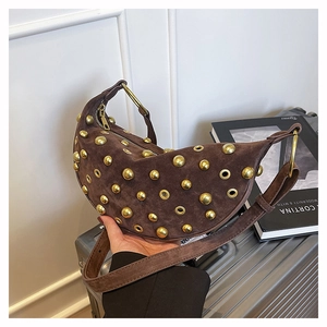 Detail of brown suede hobo bag featuring gold studs and metallic eyelet accents