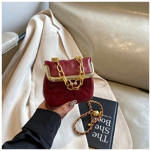 Detail of dark red quilted mini bag with gold chain and vintage metal clasp closure