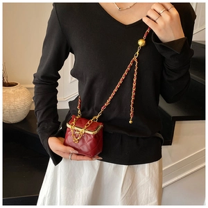 Detailed close-up of a red quilted mini crossbody bag with a gold chain strap