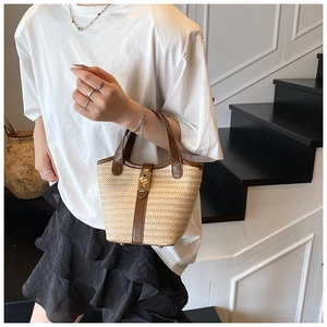 Minimalist beige woven straw bucket bag with dark brown leather straps and gold buckle