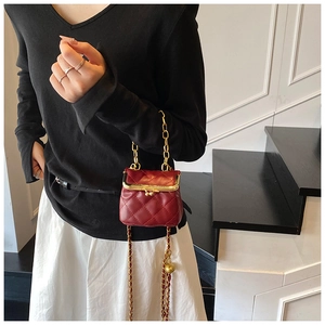Detail of wine red quilted mini crossbody bag with metal chain and decorative gold ball