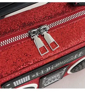 Detail of red sequined radio bag featuring dual silver metal zippers and frequency dial