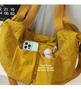 Detail of yellow nylon tote bag featuring two front pockets for easy phone and umbrella storage