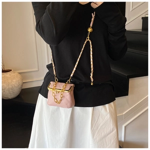 Detailed view of pink quilted mini crossbody bag with gold chain and woven leather strap