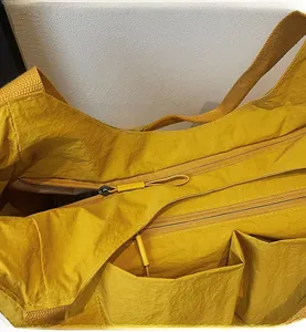 Detail of a bright yellow tote bag showing the smooth zipper closure and fabric texture