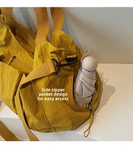 Side zipper pocket on a yellow nylon tote bag storing a compact umbrella