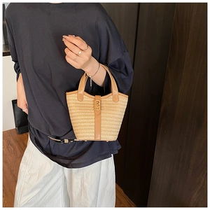 Detail of hand-woven straw bag with tan leather trim and vintage gold metal buckle