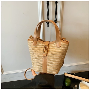 Close-up of straw bucket bag with brown leather trim and golden metal clasp lock