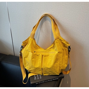 Detail view of bright yellow waterproof nylon tote bag with functional pockets and wide straps
