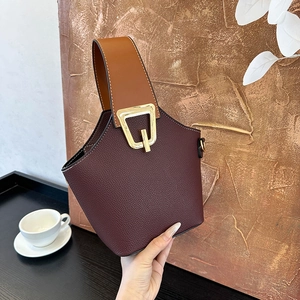 Minimalist trapezoid bucket bag in burgundy lychee leather with gold geometric hardware