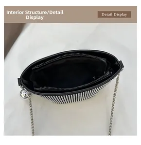 Dettaglio dell'interno in tessuto nero con tasca a zip e tracolla a catena della borsa