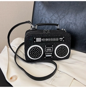 Close-up of retro radio-shaped black glitter handbag with FM frequency print and metal zipper