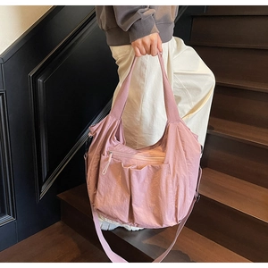 Detail of dusty rose pink nylon crossbody bag featuring multiple pockets and wide strap