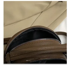 Close-up of brown litchi grain leather bag showing the dark metal zipper detail