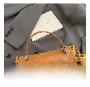 Close-up of brown quilted crossbody bag with luxury chain strap on grey blazer