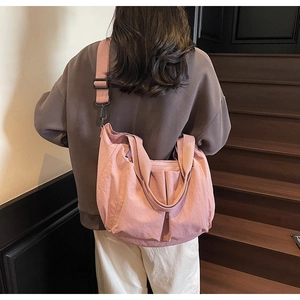 Detail of pink canvas tote bag with adjustable strap worn by model on wooden stairs