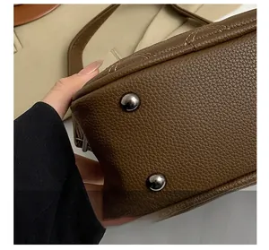 Detail view of brown leather handbag bottom with metal studs and precision stitching