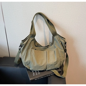Detail view of army green nylon tote bag featuring front pockets and black hardware on a seat