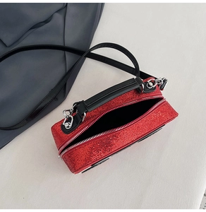 Detail of red glitter crossbody bag with black handles and silver double zippers