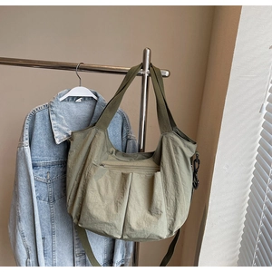 Detailed view of the olive green nylon tote bag featuring front utility pockets and texture