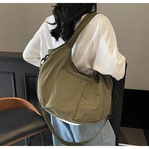 Side view of model wearing a large olive green crossbody bag made of durable nylon