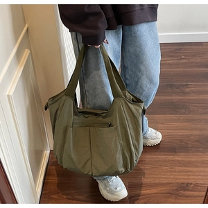 Detail of olive green nylon tote bag featuring symmetrical front pockets and wide strap