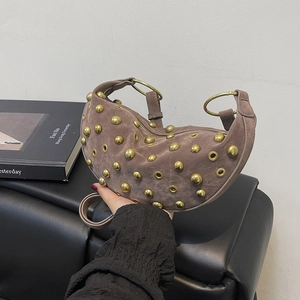 Brown suede crescent bag with gold rivets and rivets detailing held by hand