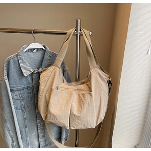 Detail of beige multi-pocket canvas tote bag hanging with stylish wide shoulder strap