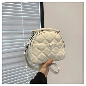 Close-up of white quilted crossbody bag showing lychee grain texture and metal zipper