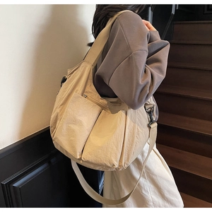 Detail of khaki nylon tote bag showing dual front pockets and adjustable shoulder strap